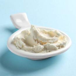 Photo of Serving spoon with tasty cream cheese on color background