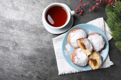 Delicious sweet buns with jam, cup of tea and decorative branches on gray table, flat lay. Space for text