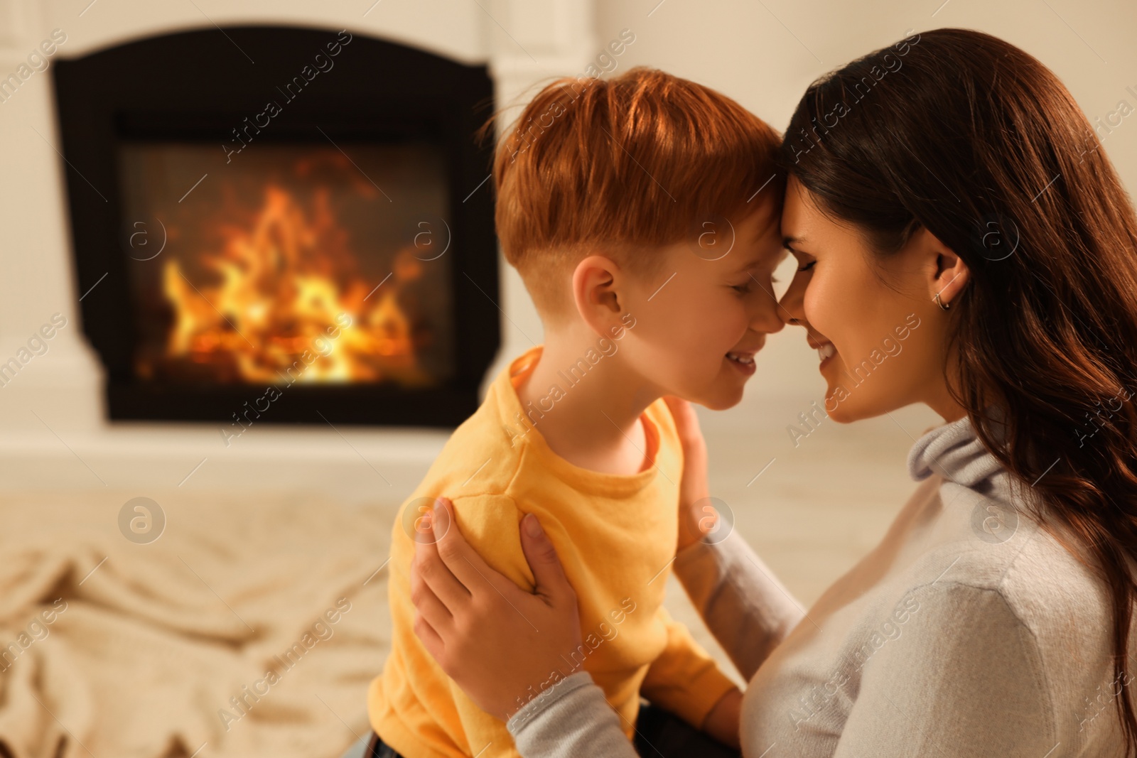 Photo of Happy mother and son spending time together near fireplace at home