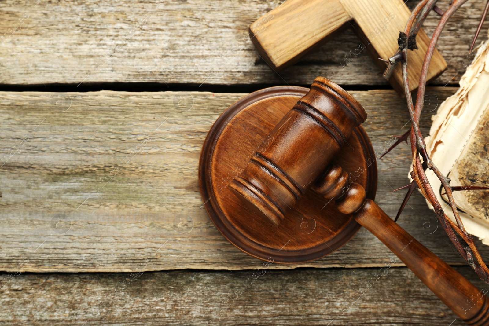 Photo of Judge gavel, cross and crown of thorns on wooden table, flat lay. Space for text