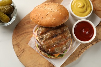 Photo of Tasty hamburger with patties, cheese and vegetables on white table, flat lay