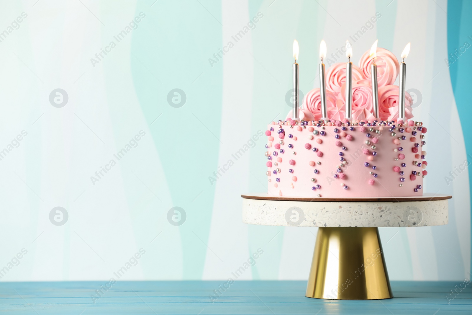 Photo of Beautifully decorated birthday cake on turquoise wooden table, space for text