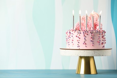 Photo of Beautifully decorated birthday cake on turquoise wooden table, space for text