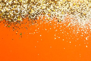 Photo of Shiny bright golden glitter on pale coral background. Space for text