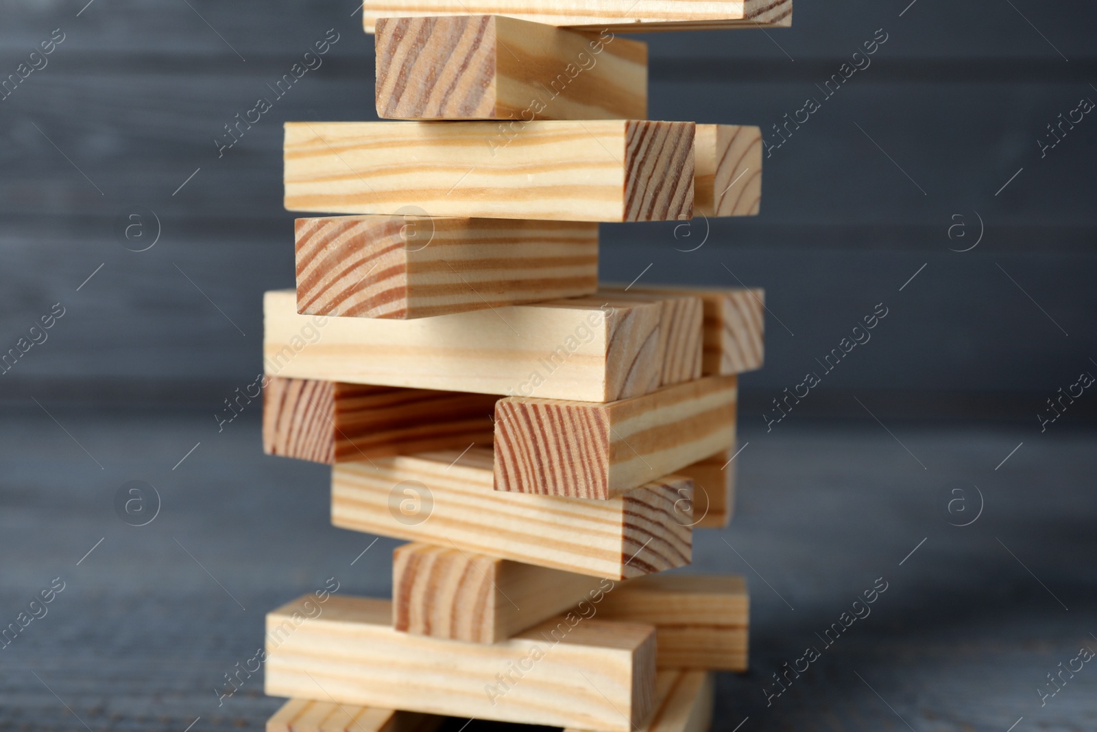 Photo of Jenga tower made of wooden blocks on grey table, closeup