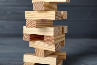 Jenga tower made of wooden blocks on grey table, closeup