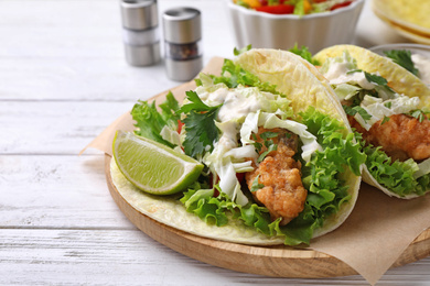 Photo of Yummy fish tacos served on white wooden table, closeup