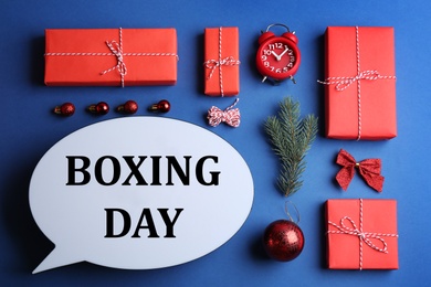 Photo of Speech bubble with phrase BOXING DAY and Christmas decorations on blue background, flat lay