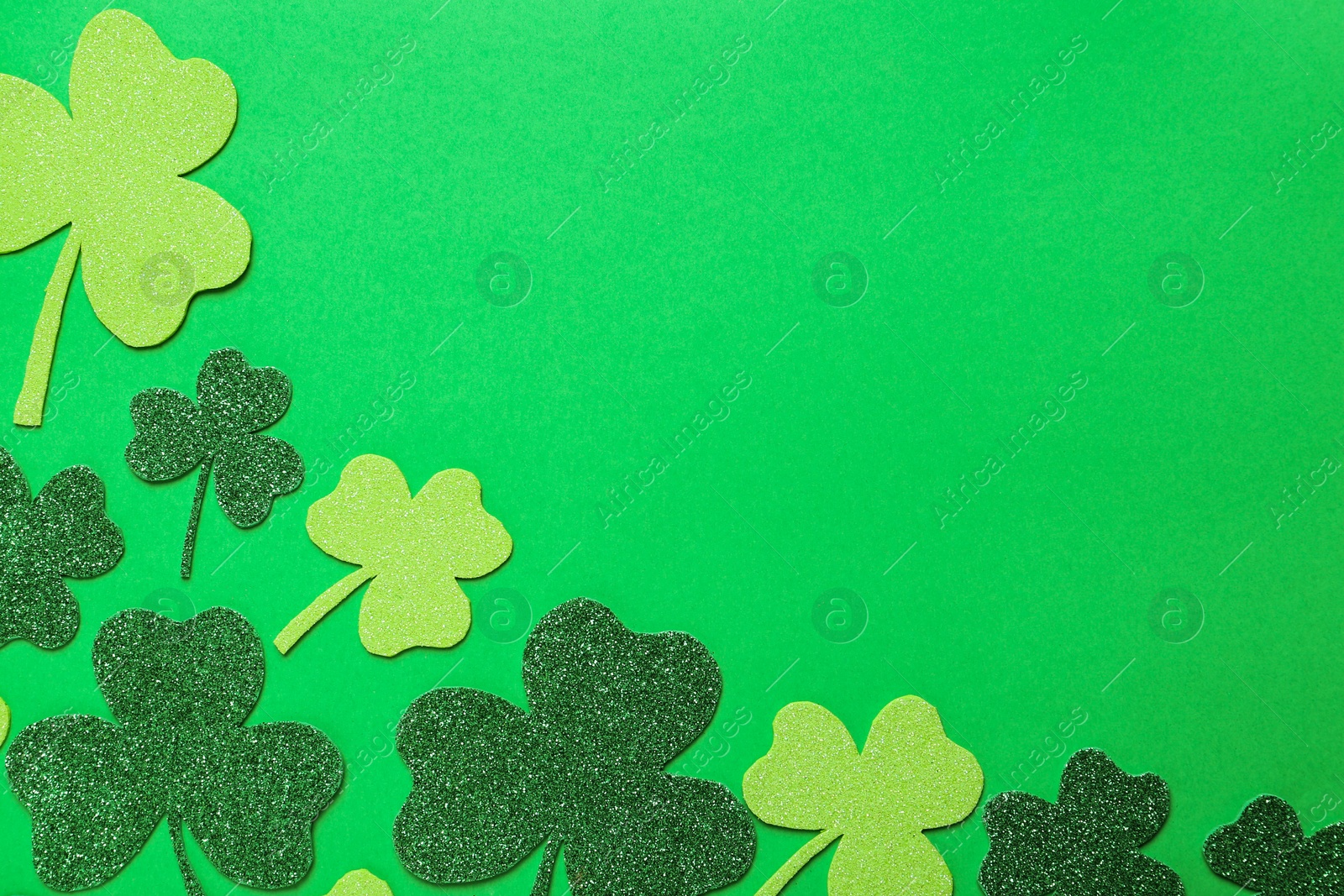 Photo of Decorative clover leaves on green background, flat lay with space for text. St. Patrick's Day celebration