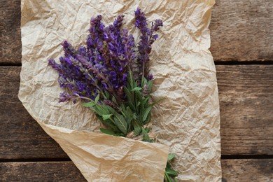 Photo of Bunch of beautiful salvia on wooden table, top view