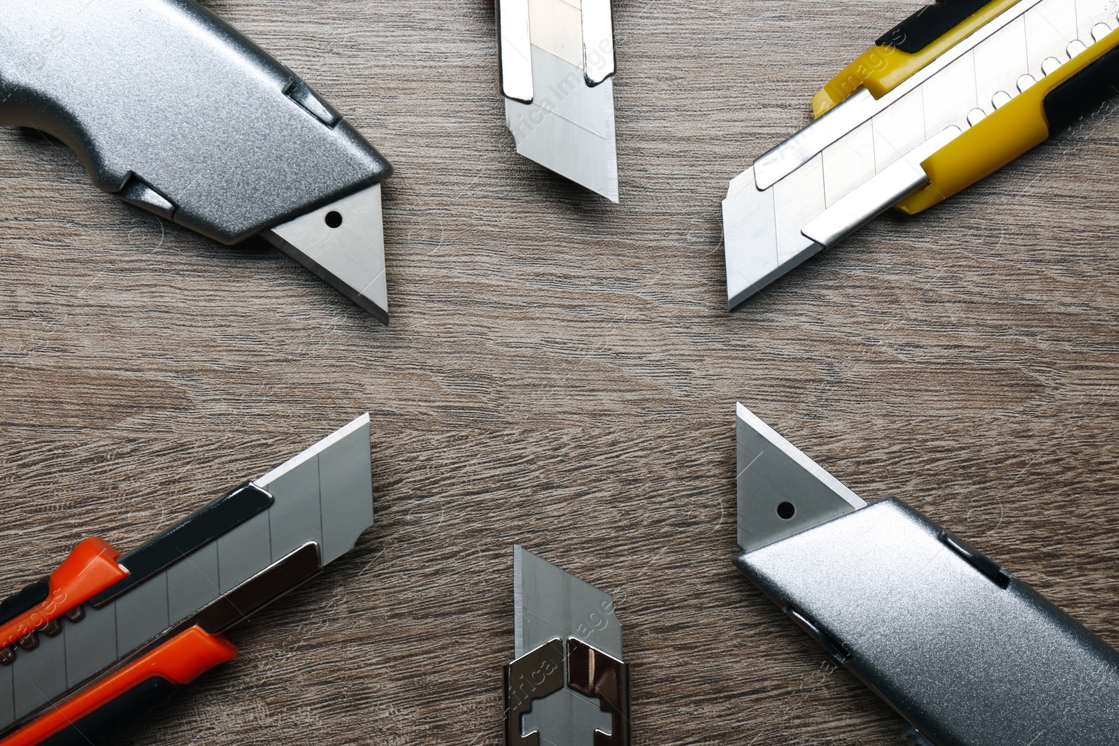 Photo of Many different utility knives on wooden table, flat lay