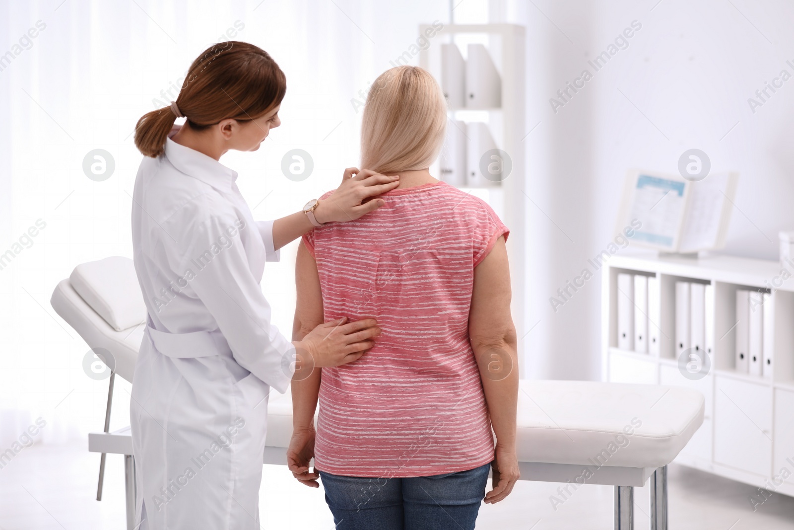 Photo of Chiropractor examining patient with back pain in clinic