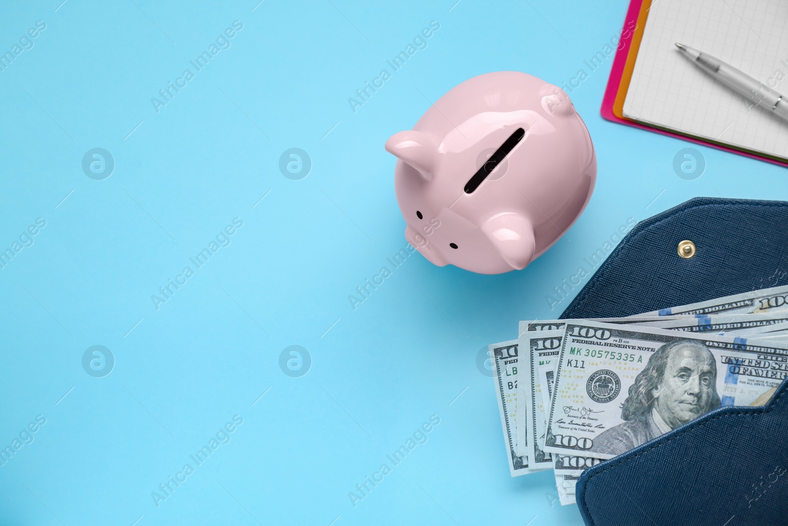 Photo of Piggy bank, notebook and wallet with banknotes on light blue background, flat lay. Space for text