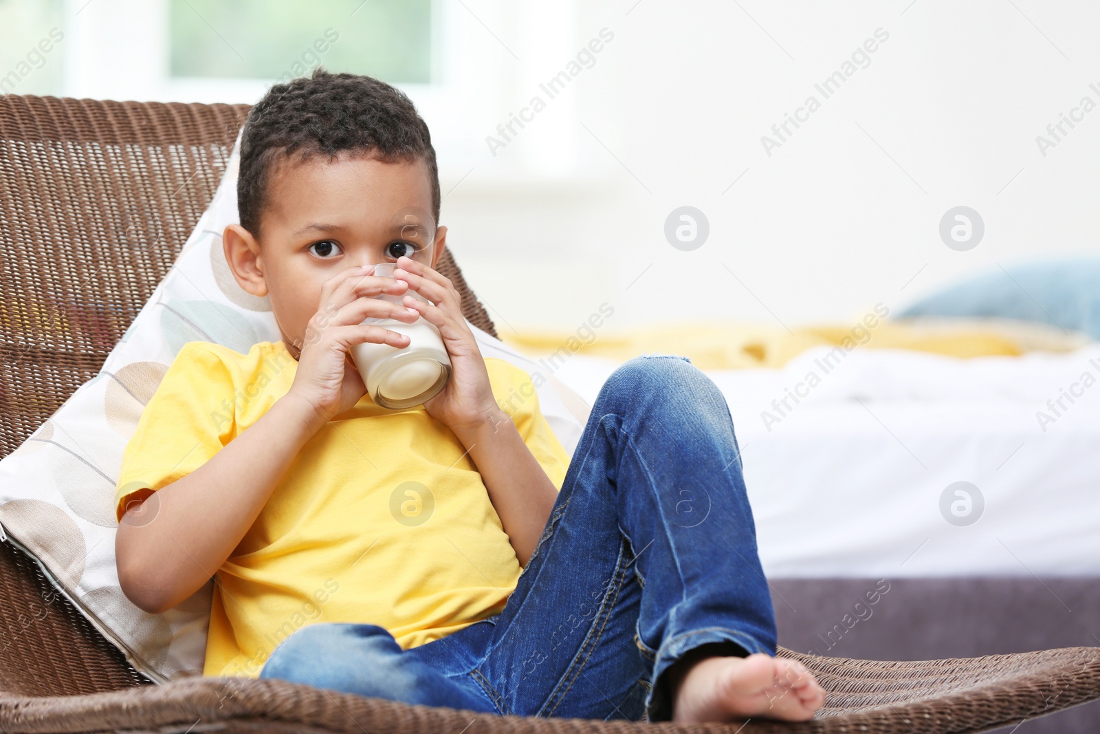 Photo of Adorable African-American boy with glass of milk at home