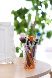 Holder with makeup brushes on table