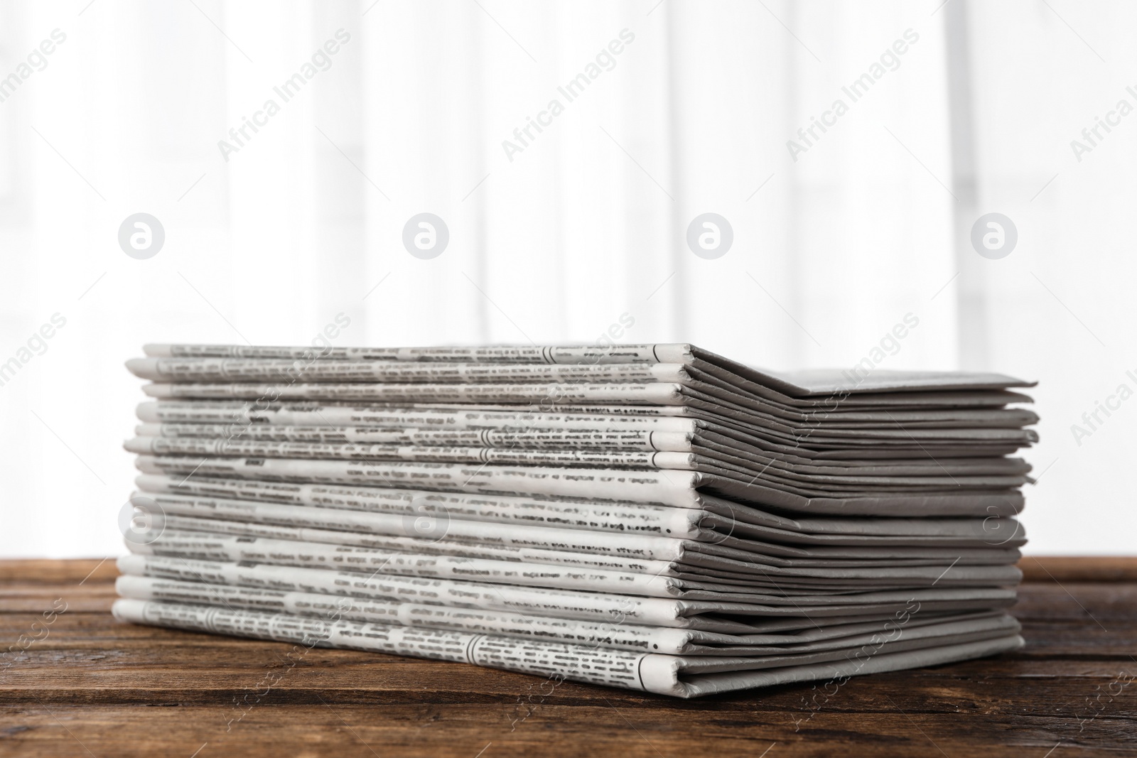 Photo of Stack of newspapers on wooden table. Journalist's work