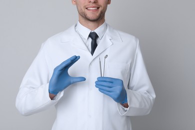 Photo of Dentist holding tools on light grey background, closeup