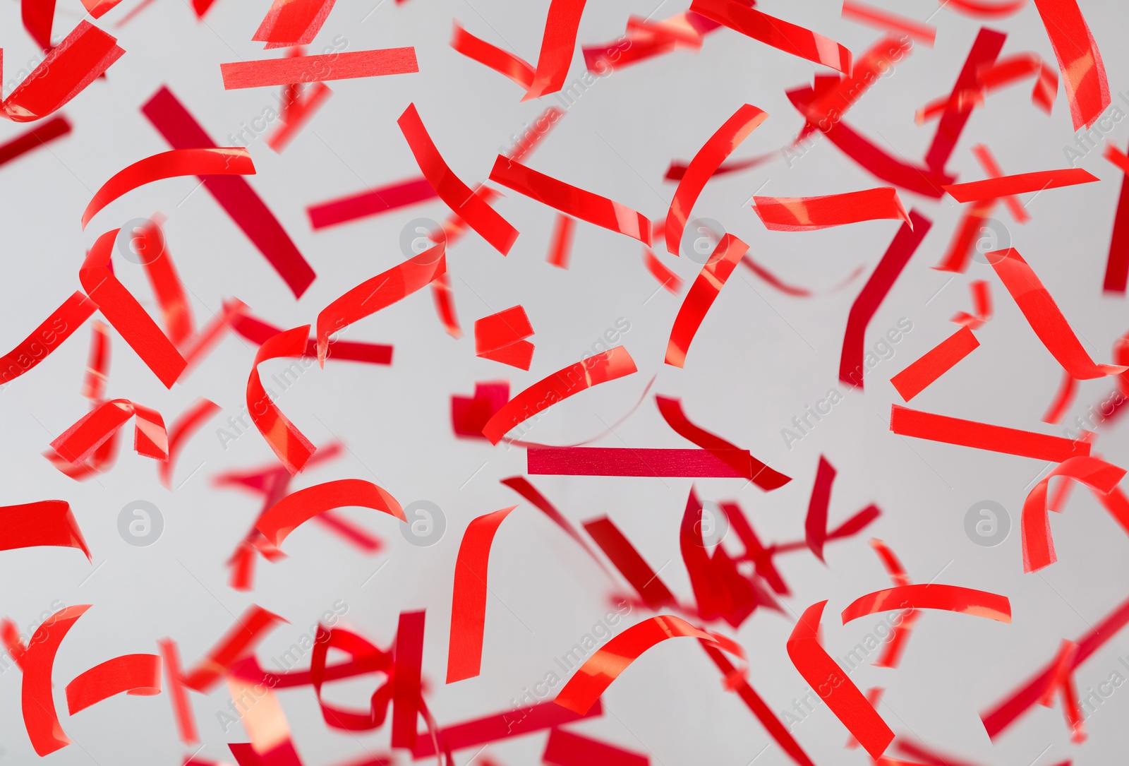 Image of Shiny red confetti falling down on light grey background