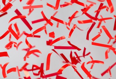 Shiny red confetti falling down on light grey background