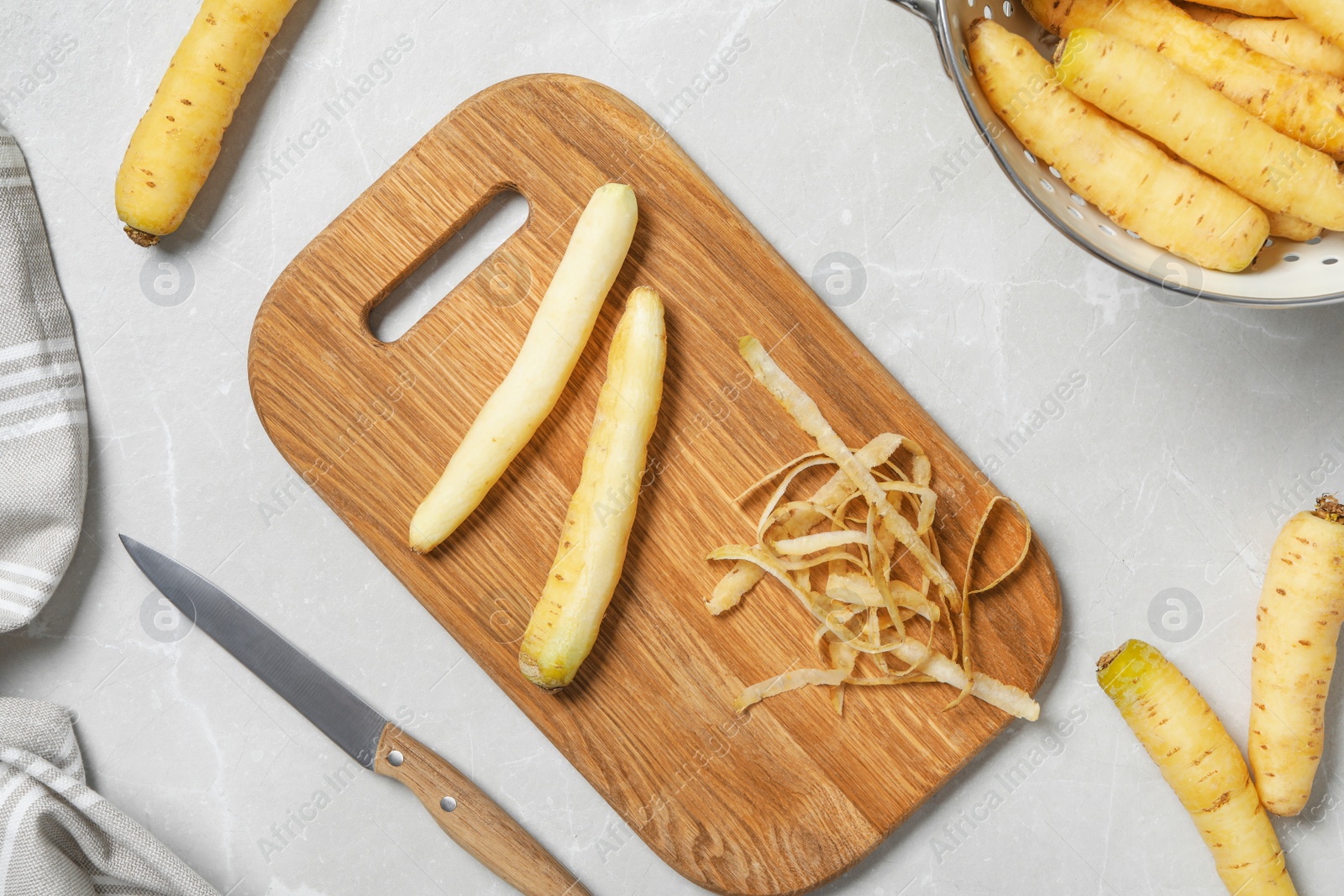 Photo of Flat lay composition with raw white carrots, knife and cutting board on light grey marble table