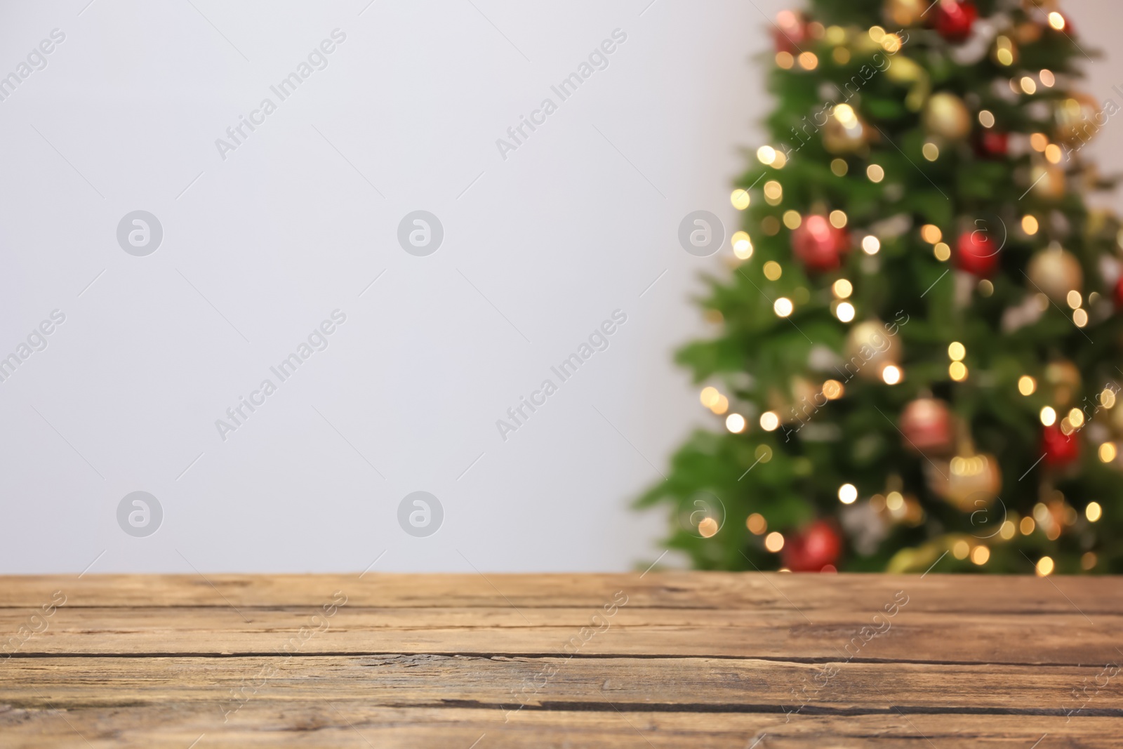 Photo of Wooden table and blurred Christmas tree with fairy lights on background