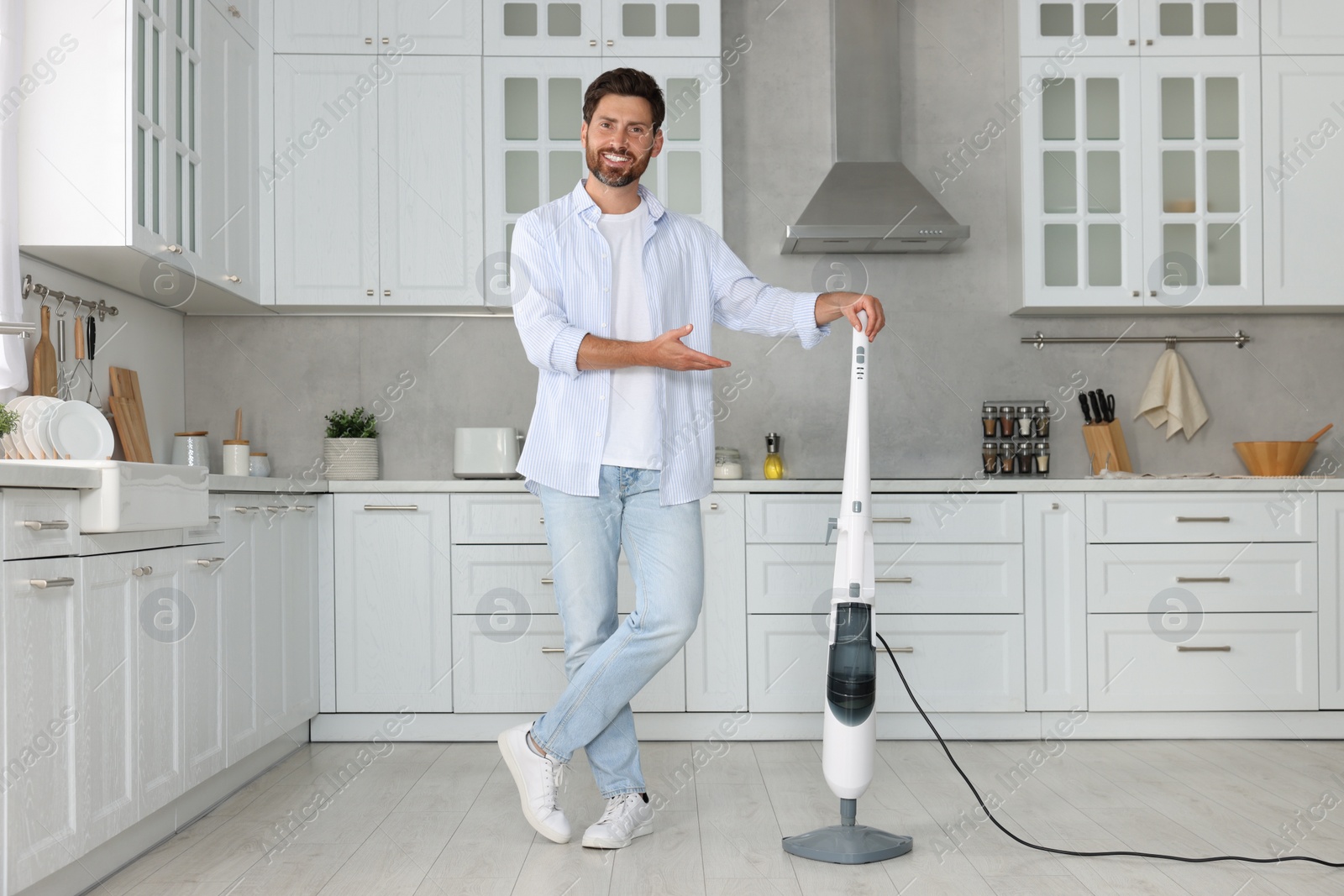 Photo of Happy man with steam mop in kitchen at home