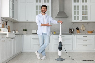 Happy man with steam mop in kitchen at home