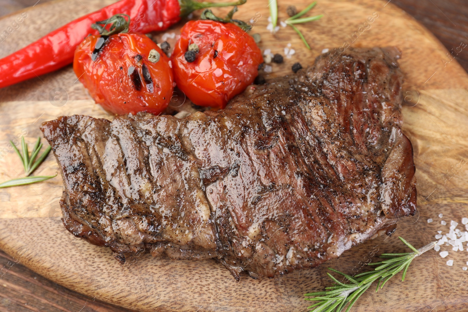 Photo of Delicious roasted beef meat, vegetables and spices on wooden table, closeup