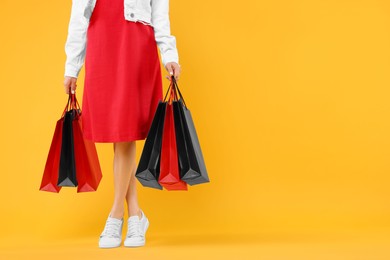 Photo of Woman with shopping bags on yellow background, closeup. Space for text