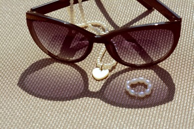 Photo of Stylish sunglasses and jewelry on grey surface, closeup