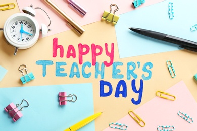 Alarm clock, text HAPPY TEACHER'S DAY and stationery on color paper