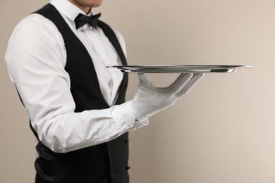 Photo of Butler with tray on beige background, closeup