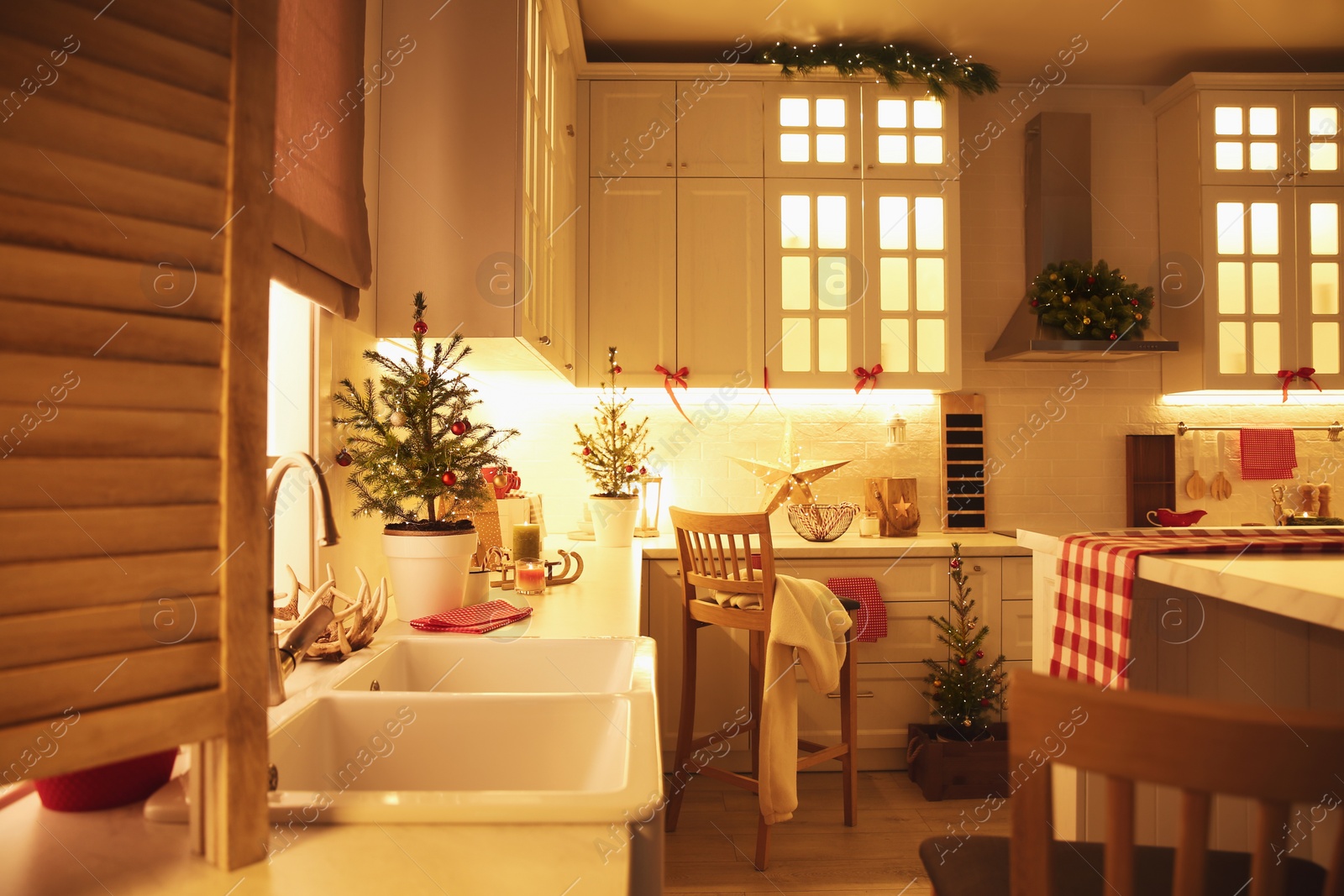 Photo of Small Christmas trees and festive decor in kitchen