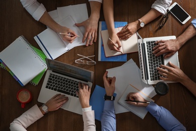 Business people discussing work matters at table in office, top view. Professional communication