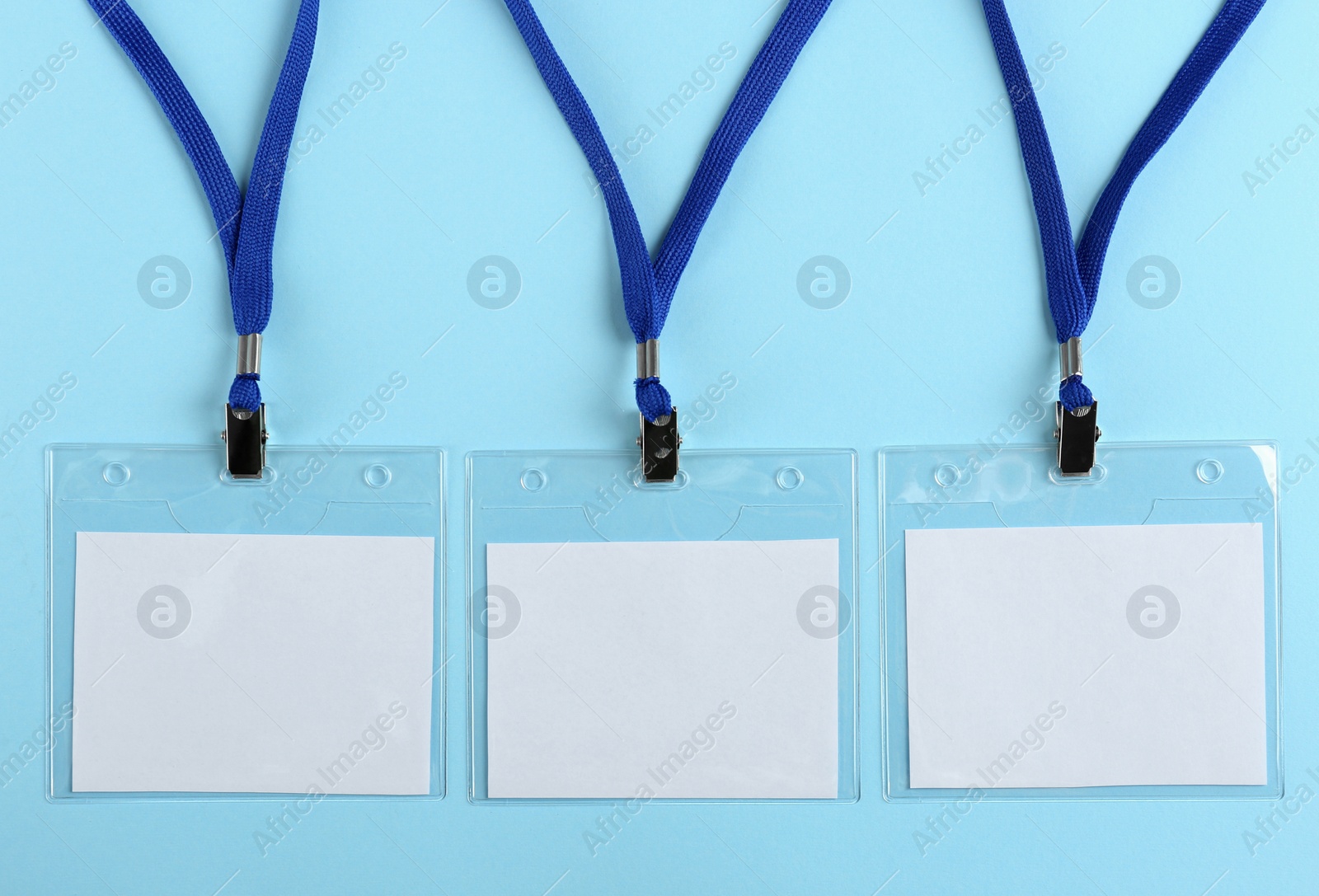 Photo of Blank badges on light blue background, flat lay. Mockup for design