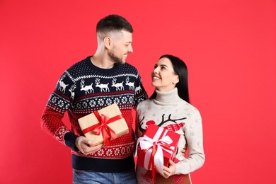Photo of Happy couple with Christmas gifts on red background