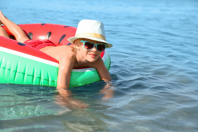 Photo of Cute little child with inflatable ring in sea on sunny day. Beach holiday