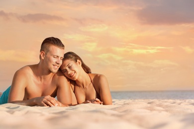 Photo of Young woman in bikini spending time with her boyfriend on beach. Lovely couple