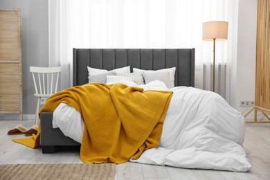 Photo of Bright plaid on bed in stylish bedroom