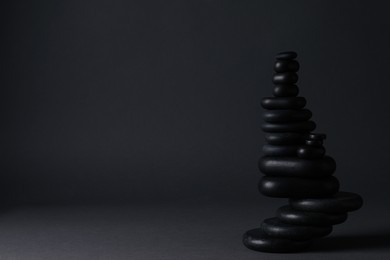 Photo of Stack of stones on black background, space for text. Harmony and balance concept