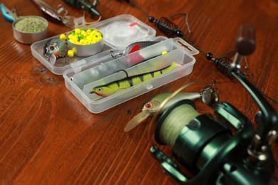 Photo of Fishing tackle. Spinning reel, lures and baits on wooden table, closeup