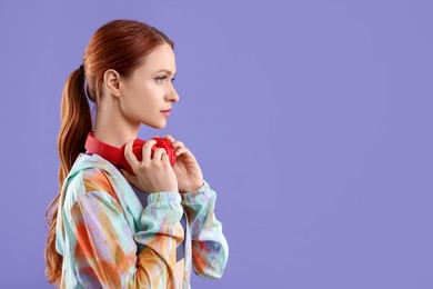 Photo of Young woman in sportswear and headphones on violet background, space for text