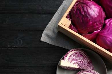 Photo of Fresh red cabbages on black wooden table, flat lay. Space for text