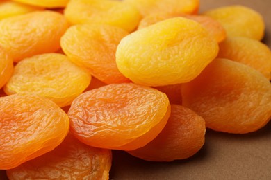 Many tasty dried apricots on pale brown background, closeup. Healthy snack
