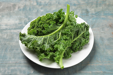 Photo of Fresh kale leaves on light blue wooden table