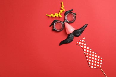 Photo of Funny face made with clown's accessories on red background, flat lay. Space for text