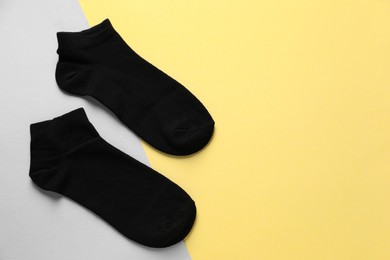 Photo of Pair of black socks on colorful background, flat lay. Space for text