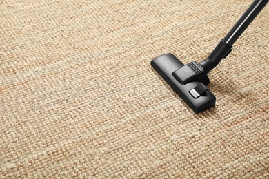 Photo of Removing dirt from beige carpet with modern vacuum cleaner. Space for text