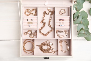 Photo of Jewelry box with stylish golden bijouterie on white wooden table, flat lay