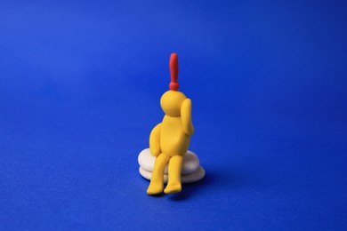 Human figure made of yellow plasticine with exclamation mark as solution idea on blue background